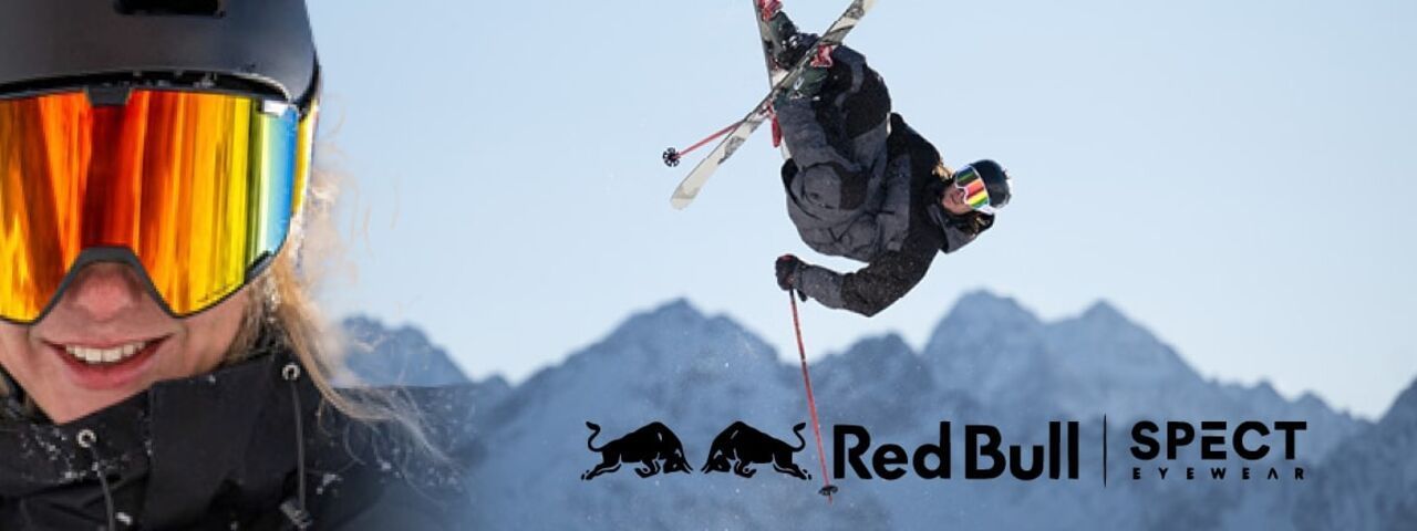 Freestyle-Skifahrer mit Red Bull SPECT Skibrille bei spektakulärem Sprung vor verschneiter Bergkulisse – Action und Style im Schnee.