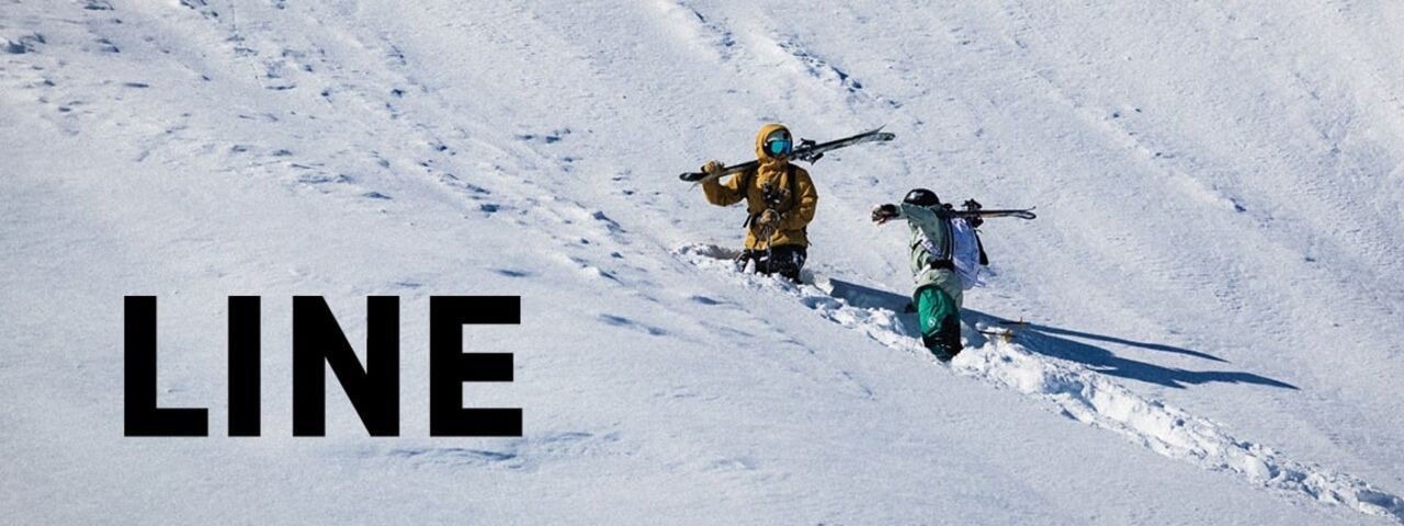 Zwei Freerider tragen ihre Ski durch unberührten Tiefschnee – auf dem Weg zum nächsten Run mit LINE Skis.