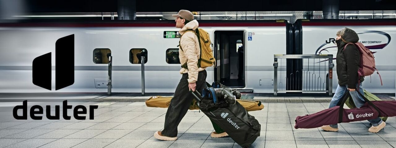 Outdoor-Sportler mit Deuter-Backpacks und Skibags vor einem modernen Zug – bereit für den Wintersport-Trip mit funktionaler Reiseausrüstung.