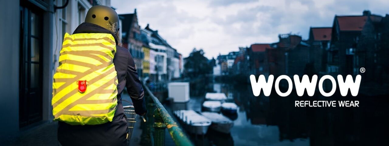 Radfahrer mit reflektierendem WOWOW-Rucksacküberzug und Rücklicht – optimale Sichtbarkeit bei Dämmerung in der Stadt.