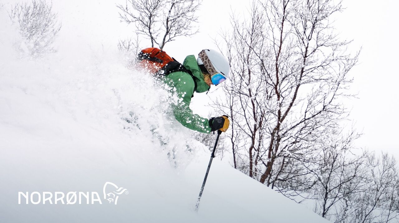 Freerider in grüner Jacke pflügt durch tiefen Pulverschnee – perfekte Powder-Action mit NORRØNA-Outdoorausrüstung.