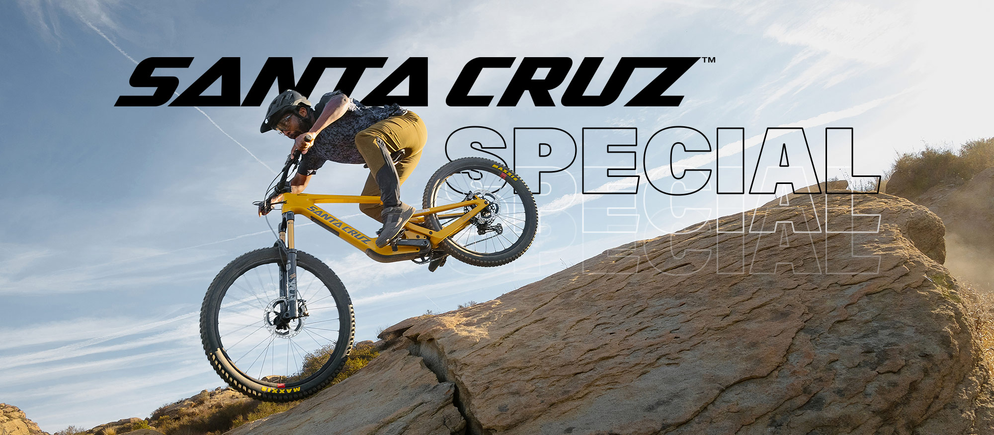 Actionaufnahme eines Mountainbikers auf einem gelben Santa Cruz Bike beim Sprung über einen steinigen Trail.