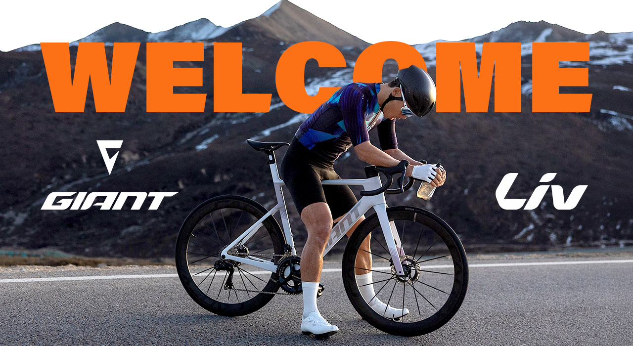 Rennradfahrer mit Giant Liv Rennrad vor alpiner Bergkulisse und „Welcome“-Schriftzug