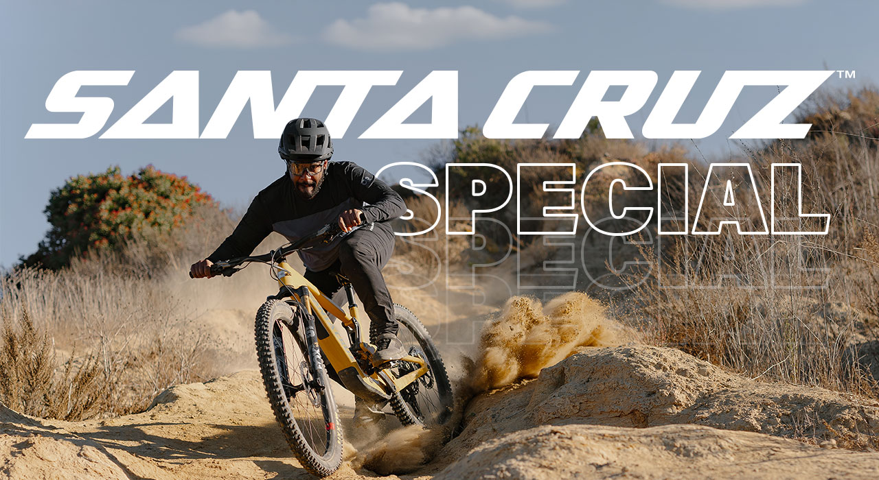 Santa Cruz Specials. Mountainbiker rast mit einem gelben E-Bike durch eine sandige Landschaft.